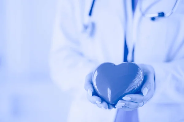 Doctora con estetoscopio sosteniendo el corazón, sobre fondo claro —  Fotos de Stock