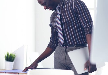 Ofiste bilgisayar ve planlarla çalışan Afrikalı Amerikalı bir mimar.