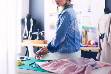 Moda tasarımcısı kadın stüdyoda tasarımları üzerinde çalışıyor.