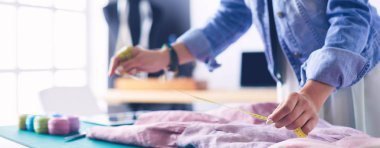 Moda tasarımcısı kadın stüdyoda tasarımları üzerinde çalışıyor.