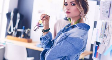 Moda tasarımcısı kadın stüdyoda tasarımları üzerinde çalışıyor.