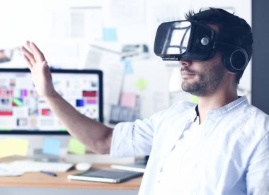 Genç erkek yazılım programcısı ofiste üç boyutlu sanal gerçeklik gözlükleriyle yeni bir uygulama test ediyor..