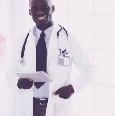 Tablet bilgisayarlı siyahi bir doktor hastanede bekliyor.