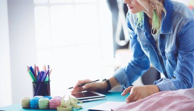 Moda tasarımcısı kadın stüdyoda tasarımları üzerinde çalışıyor.