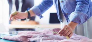 Moda tasarımcısı kadın stüdyoda tasarımları üzerinde çalışıyor.