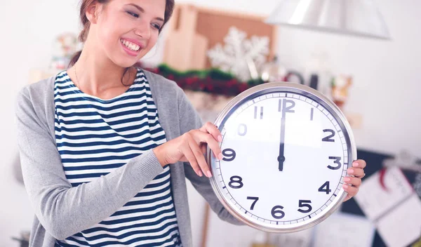 Happy young woman showing clock in christmas decorated kitchen — Stock Photo, Image