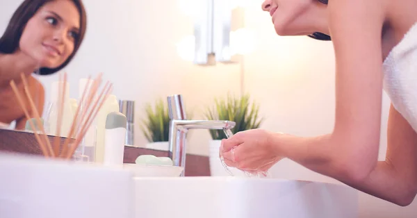 Mladá žena mytí obličeje s čistou vodou v koupelně — Stock fotografie