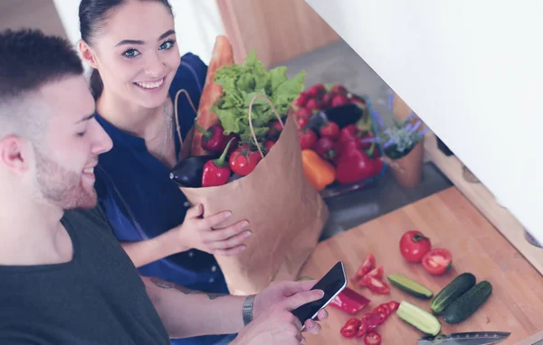 Coppia felice utilizzando smartphone in piedi in cucina — Foto Stock