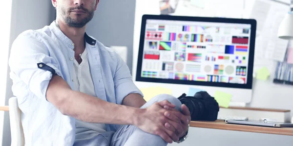 Porträt eines jungen Designers, der im Grafikstudio vor Laptop und Computer sitzt, während er online arbeitet. — Stockfoto