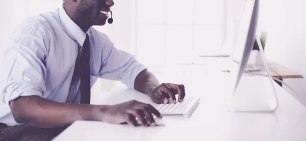 Afrikansk amerikansk affärsman på headset arbetar på sin bärbara dator — Stockfoto