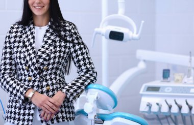 Kadın dişçi ofisinde gülümsüyor.