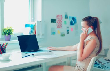 Ofiste masada oturan, dizüstü bilgisayarla çalışan, belge tutan çekici kadın