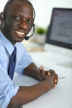 Kulaklıklı Afro-Amerikan işadamı laptopuyla çalışıyor.