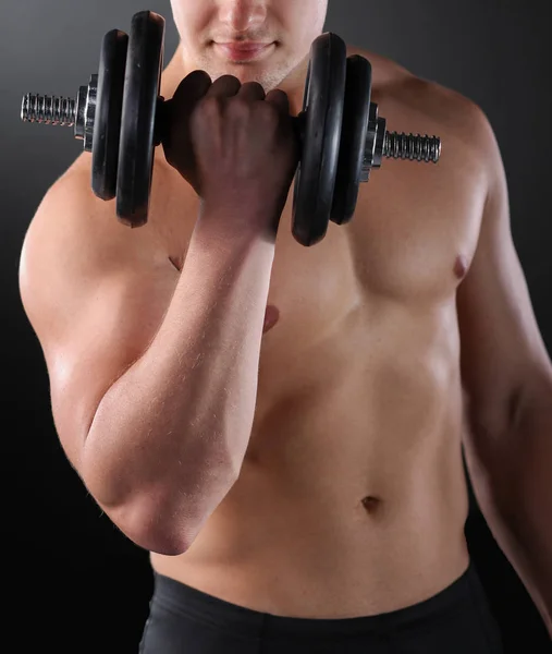 Muscular guy doing exercises with dumbbells over dark background — 스톡 사진