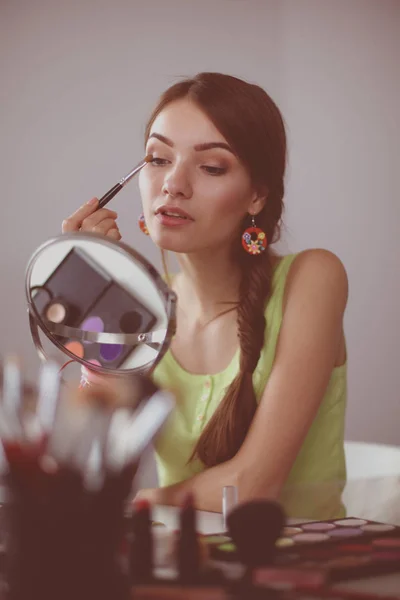 Genç ve güzel bir kadın aynanın yanında makyaj yapıyor. — Stok fotoğraf