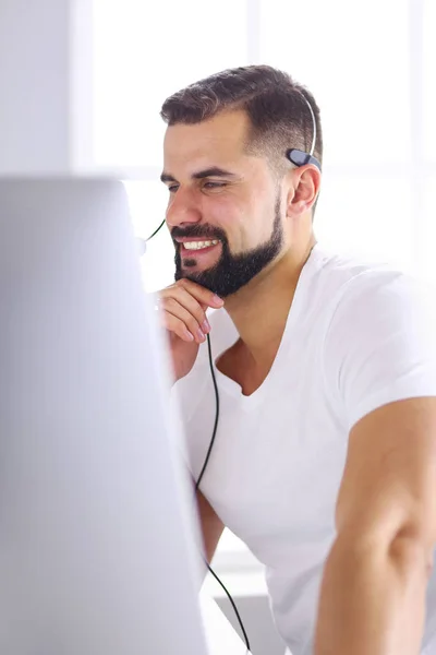 Egy fiatal férfi portréja fejhallgatóval egy laptop előtt. — Stock Fotó