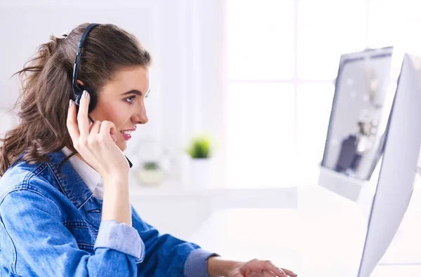 Jovem encantadora feliz sentada e trabalhando com laptop usando fone de ouvido no escritório — Fotografia de Stock