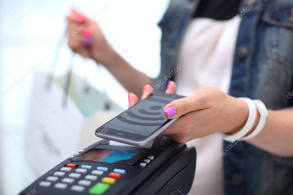 Customer is paying with smartphone in shop using NFC technology. NFC technology. Customer is paying