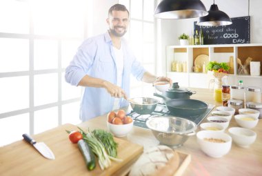 Adam ev mutfağında lezzetli ve sağlıklı yemekler hazırlıyor.