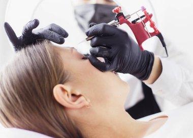 Mikro patenli kaşlar güzellik salonunda çalışır. Kaşları renkli bir kadın.