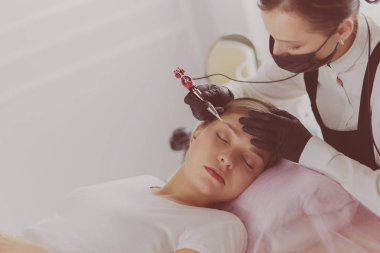 Güzellik salonunda kaş makyajı yapılan genç bir kadın.