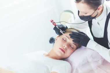 Güzellik salonunda kaş makyajı yapılan genç bir kadın.