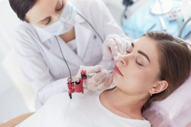 Kırmızı dudaklı genç bir kız kalıcı makyaj, mikro pigmentasyon