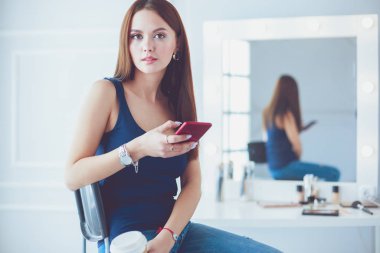Kafede kahve içip cep telefonuyla konuşan genç bir kadın.