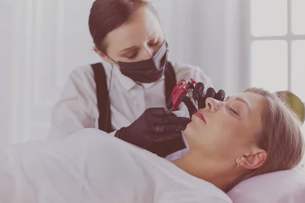 Cosmetoloog die permanente make-up op wenkbrauwen aanbrengt — Stockfoto