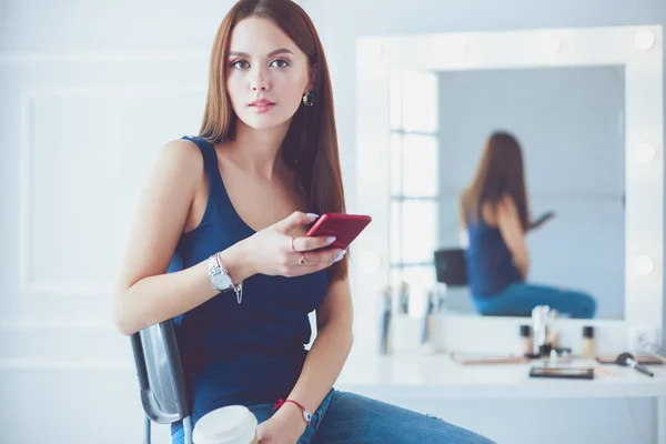 咖啡馆边喝咖啡边用手机聊天的年轻女人 — 图库照片
