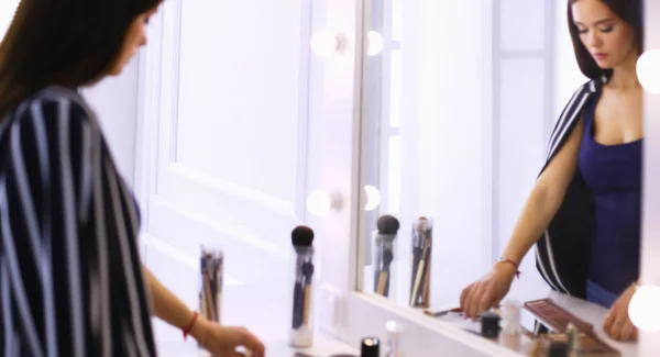 Reflexão da jovem bela mulher aplicando sua maquiagem, olhando em um espelho — Fotografia de Stock