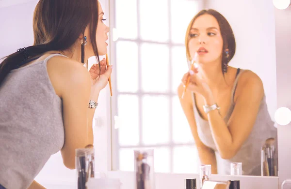 Jeune femme appliquant du rouge à lèvres devant un miroir — Photo