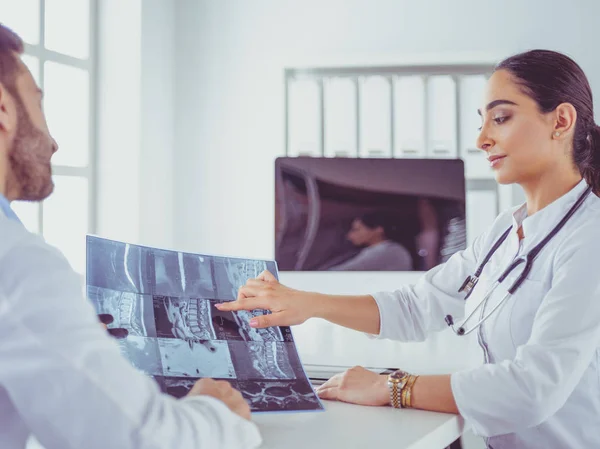Zwei Ärzte untersuchen Röntgenbild und beraten sich im hellen Büro — Stockfoto