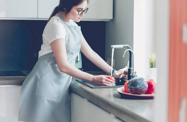 Женщина моет помидоры в кухонной раковине — стоковое фото