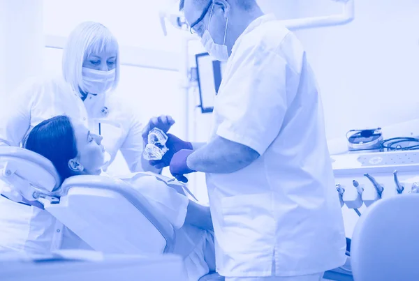 Odontólogos masculinos examinando y trabajando en mujeres jóvenes pacientes.Dentistas oficina. — Foto de Stock