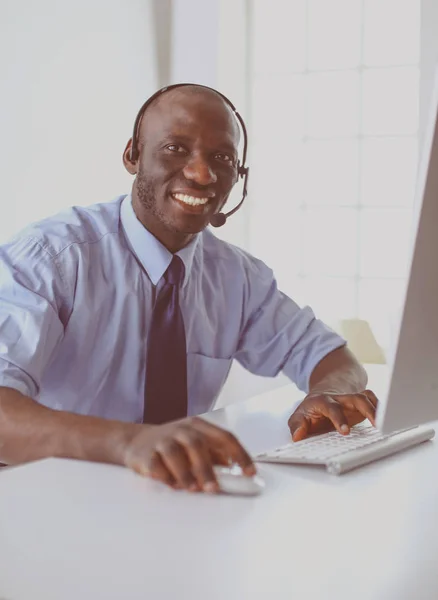 Hombre de negocios afroamericano con auriculares trabajando en su computadora portátil — Foto de Stock