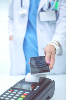 Doktor ödeme terminalini elinde tutuyor. Sağlık hizmetlerinin parasını ödüyorum. Doktor.