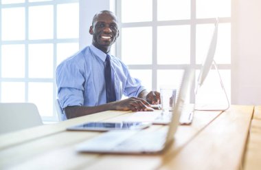 Kulaklıklı Afro-Amerikan işadamı laptopuyla çalışıyor.