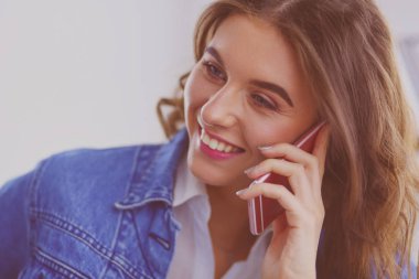 Kafede kahve içip cep telefonuyla konuşan genç bir kadın.