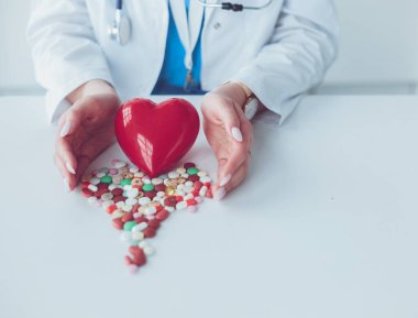 Masada kırmızı kalbi ve steteskopu olan kardiyolog.