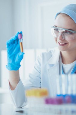 Laboratuvarda sıvı yeşil çözeltiye bakan bir tıbbi veya bilimsel araştırmacı ya da doktor