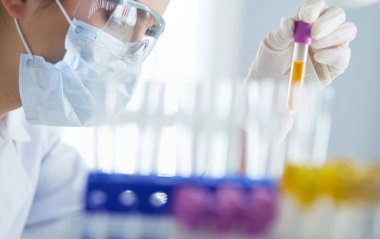 Laboratuvarda sıvı yeşil çözeltiye bakan bir tıbbi veya bilimsel araştırmacı ya da doktor