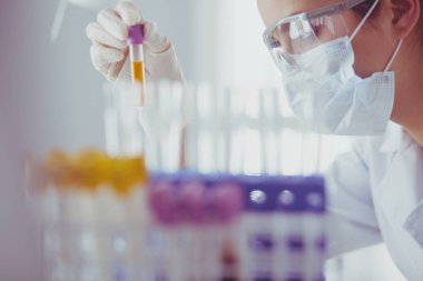 Laboratuvarda sıvı yeşil çözeltiye bakan bir tıbbi veya bilimsel araştırmacı ya da doktor