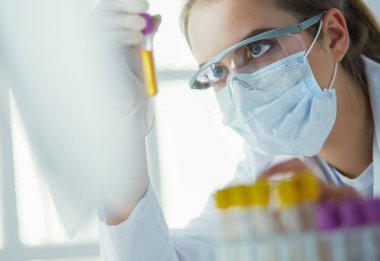 Hastanedeki kan örneğini analiz eden güzel bir kadın laboratuvar asistanı portresi.