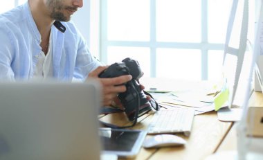 İnternette çalışırken bilgisayarın ve dizüstü bilgisayarın önünde grafik stüdyosunda oturan genç tasarımcının portresi.
