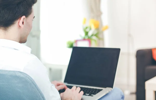 Glücklicher Mann, der am Tisch sitzt und zu Hause Laptop benutzt — Stockfoto