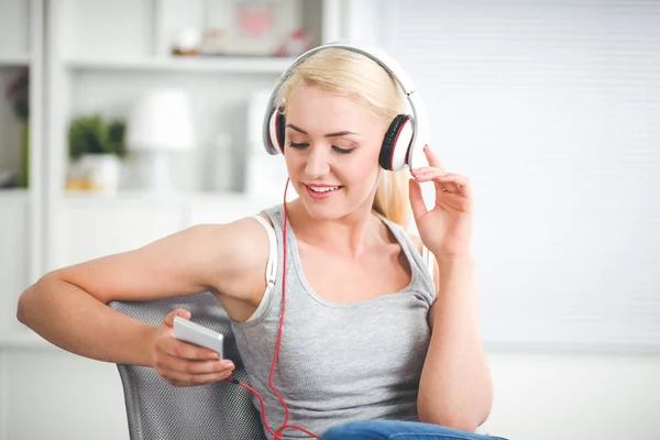 Jonge mooie vrouw thuis zitten op de bank en luisteren muziek — Stockfoto