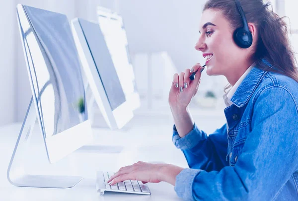 Donna d'affari sorridente con auricolare utilizzando il computer portatile alla scrivania nel lavoro — Foto Stock