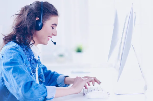 Jovem encantadora feliz sentada e trabalhando com laptop usando fone de ouvido no escritório — Fotografia de Stock