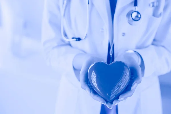Női orvos sztetoszkóppal tartó szív, világos alapon — Stock Fotó